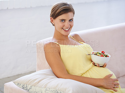 Buy stock photo Shot of a beautiful pregnant woman relaxing on the sofa while eating a fresh salad