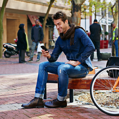 Buy stock photo Bench, city and smile with man, smartphone and bicycle with adventure and joy with internet and social media. Person, outdoor or New York with hipster and cellphone with connection or typing with app