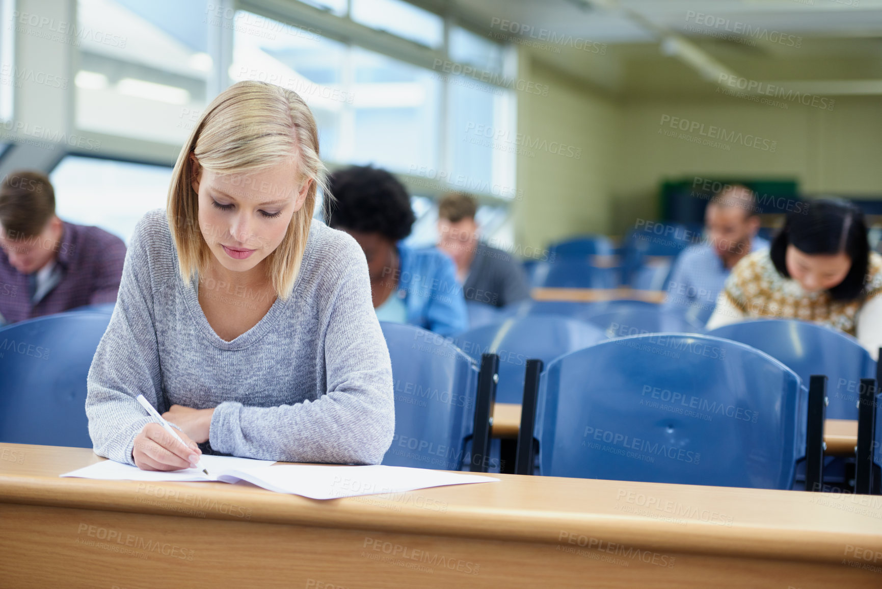 Buy stock photo Lecture, woman and student writing, focus and education for development, knowledge and learning. Female person, young people or group in a room, notes and ambition at university, scholarship and test