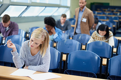 Buy stock photo Exam, classroom and student with pen for thinking, assessment and writing at campus. Woman, planning and sitting with paper for brainstorming, education and growth of knowledge in university class