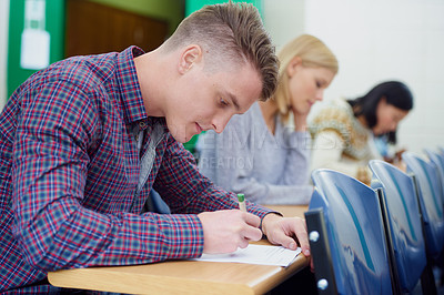Buy stock photo University student, desk and writing exam in classroom for education assessment for knowledge, diploma or scholarship. Men, woman and test in London lecture hall or study document, academy or college