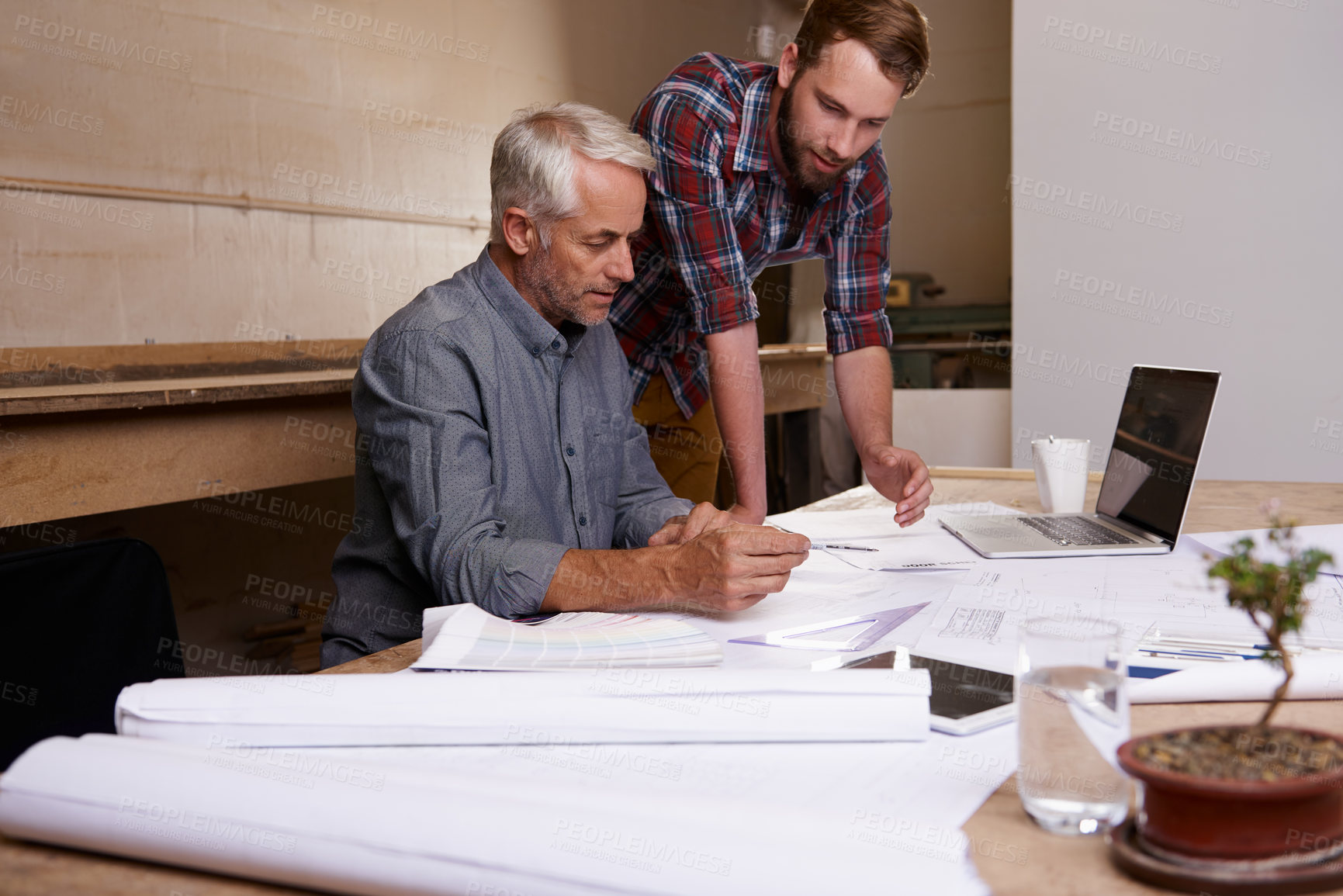 Buy stock photo Architect, teamwork and men with blueprint in workshop for collaboration. Senior engineer, design and father and son planning, discussion and working on building project of apprentice with mentor.