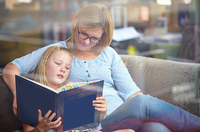 Buy stock photo A cute young girl sitting next to her mother while they read a book