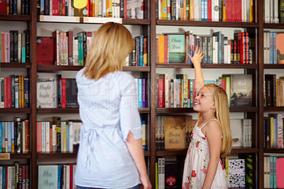 Buy stock photo Young blond girl reaching for a book in the library