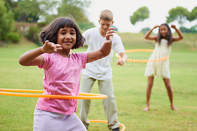 Buy stock photo Three children playing with hula hoops outside