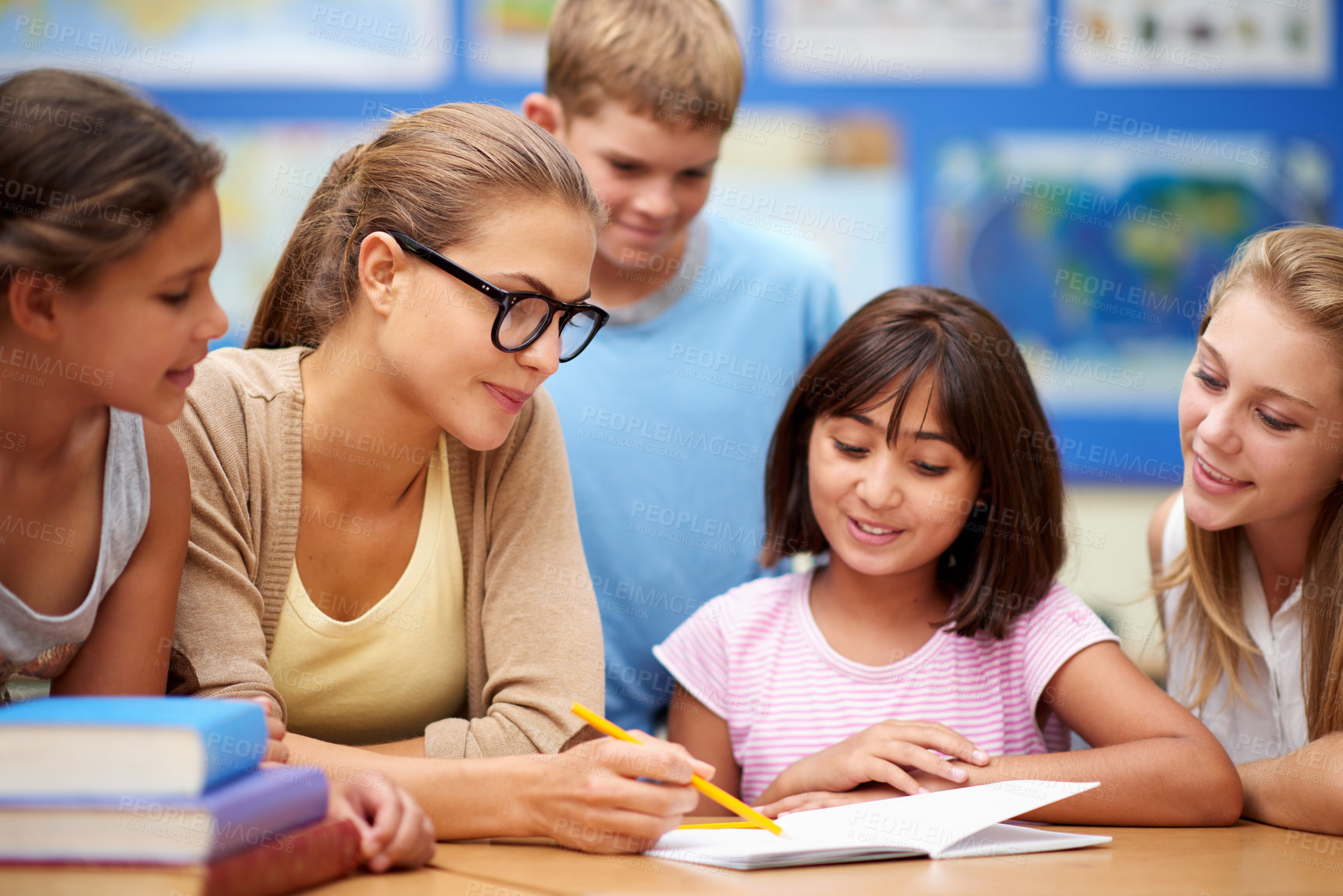 Buy stock photo Happy teacher, students and writing for education, learning or tutoring in classroom at school. Woman, mentor or educator helping young kids or children with books for studying or literature in class