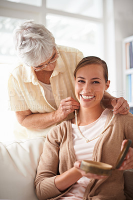 Buy stock photo Home, necklace and portrait of senior mother and woman for present, gift and surprise in living room. Family, happy and daughter with mom giving pearls on sofa for celebration, birthday and bonding