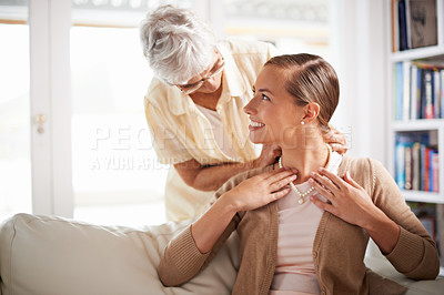 Buy stock photo Love, necklace and senior mother with woman for gift, present and surprise in living room. Family jewels, home and happy daughter with mom giving pearls on sofa for celebration, birthday and bonding