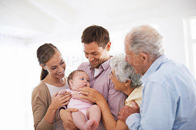 Buy stock photo Portrait of a smiling young couple holding their baby girl while standing with their senior parents