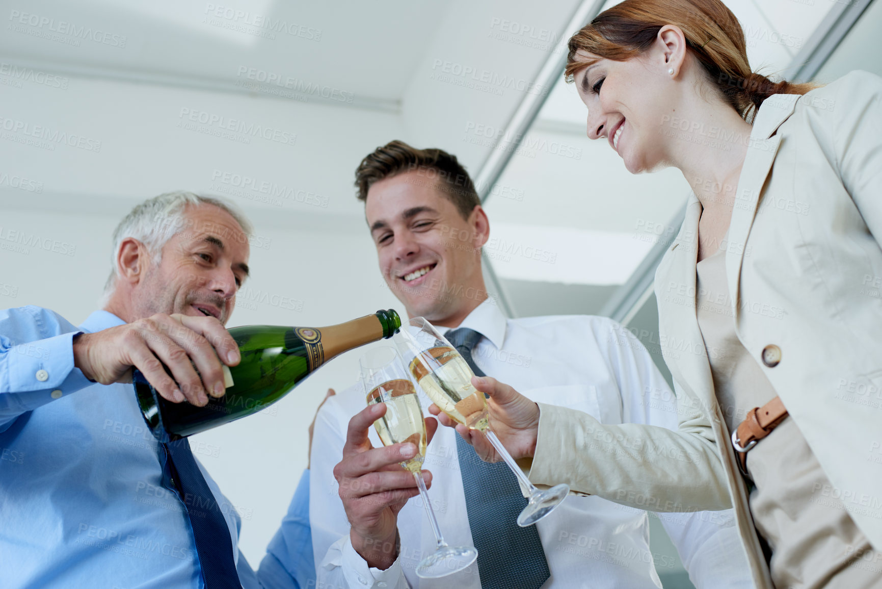 Buy stock photo Champagne, bottle or happy business people in office party in celebration of target or success. Pour, glass low angle or cheers for winning goal with team, growth or group of colleagues in workplace