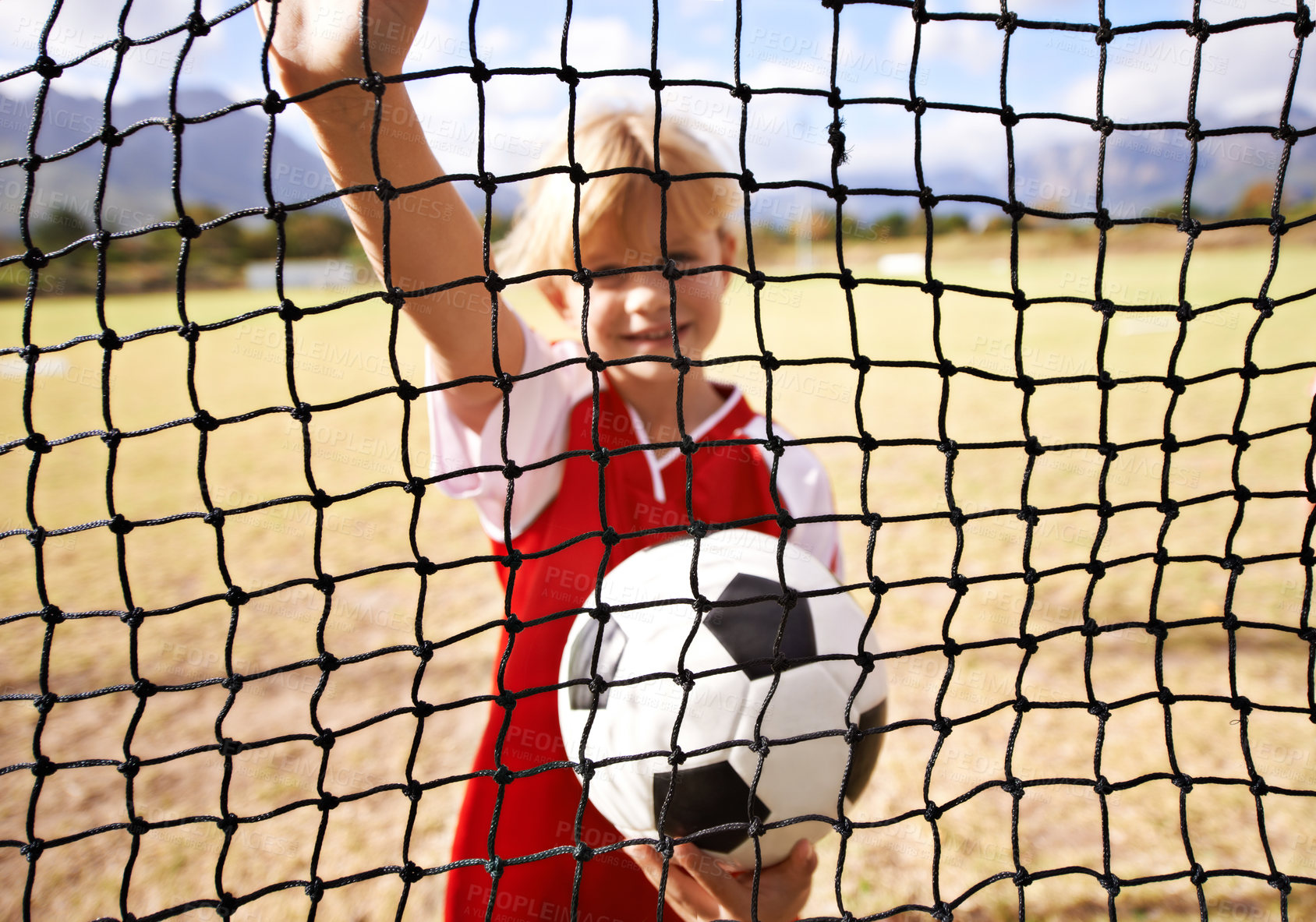 Buy stock photo Little girl, soccer player and ball on goal net, smile and happy for game, field and child. Outdoor, playful or sport for childhood, portrait and athlete for match, alone or outside on football pitch