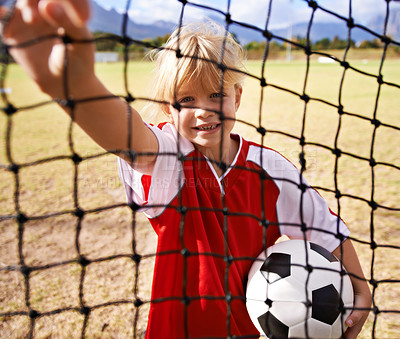 Buy stock photo Little girl, soccer player and ball on goal net, smile and happy for game, field and child. Outdoor, playful and sport for childhood, portrait and athlete for match, alone and outside on pitch