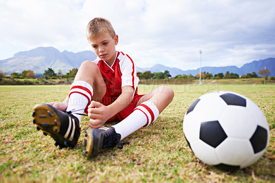 Buy stock photo Boy, soccer player and ball with shoe laces, field and ready for game, shoes and child. Outdoor, playful and sport for childhood, person and athlete for match, alone and outside on football pitch