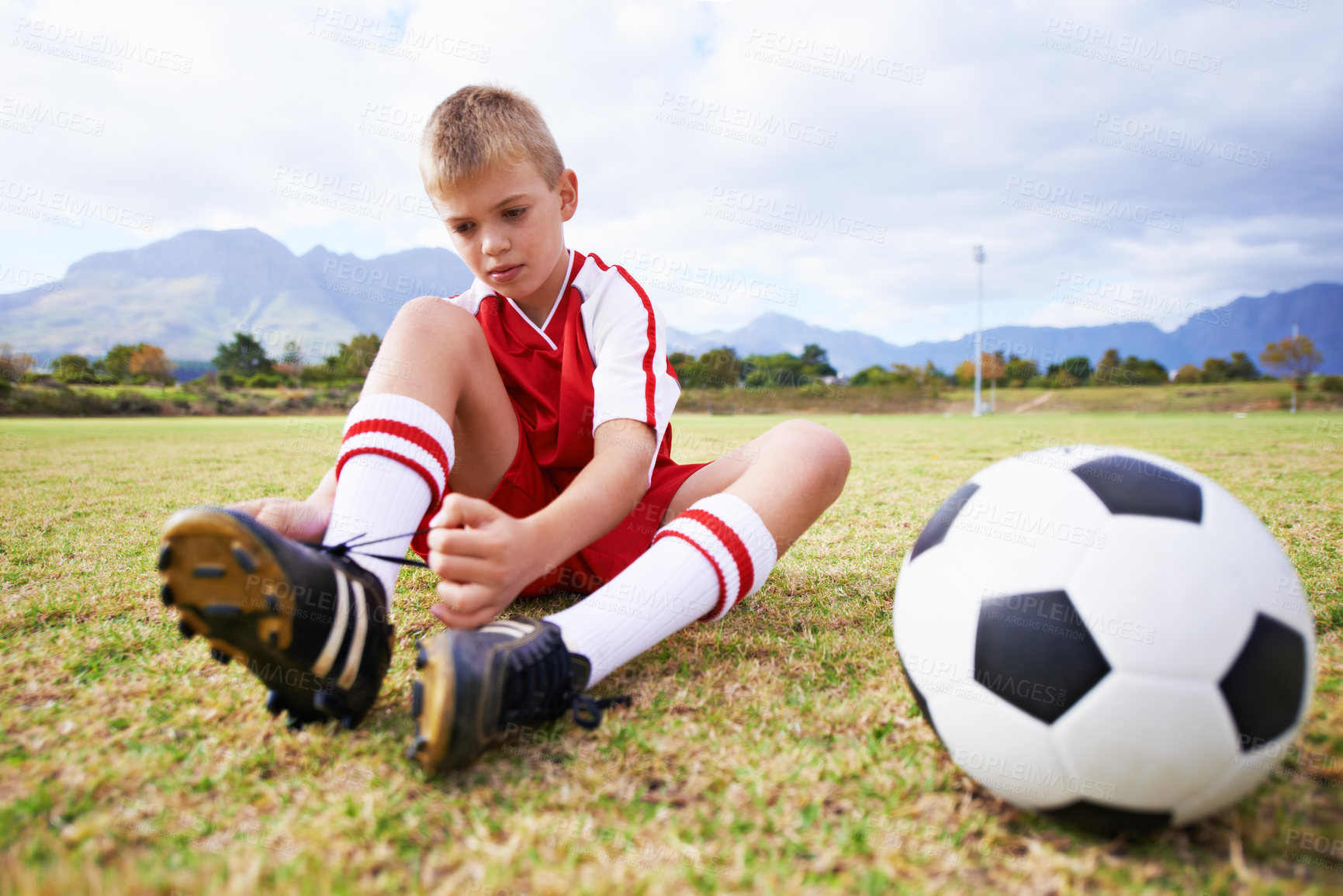 Buy stock photo Boy, soccer player and ball with shoe laces, field and ready for game, shoes and child. Outdoor, playful and sport for childhood, person and athlete for match, alone and outside on football pitch