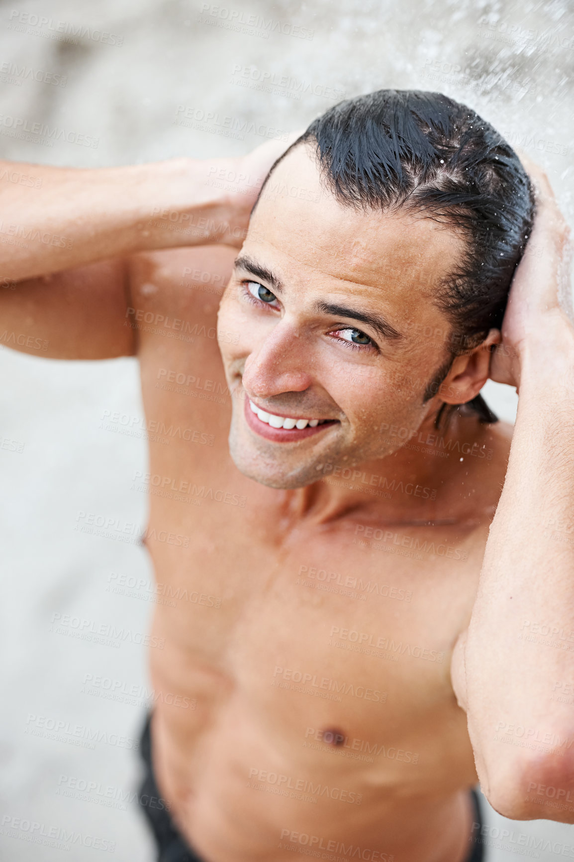 Buy stock photo Man, smile and water shower in outdoors, beach and hydrate or clean after swimming, relax and travel. Happy male person, portrait and vacation for fun, water splash and fresh on holiday or getaway 