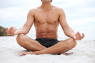 Buy stock photo Young handsome man sitting on the beach meditating