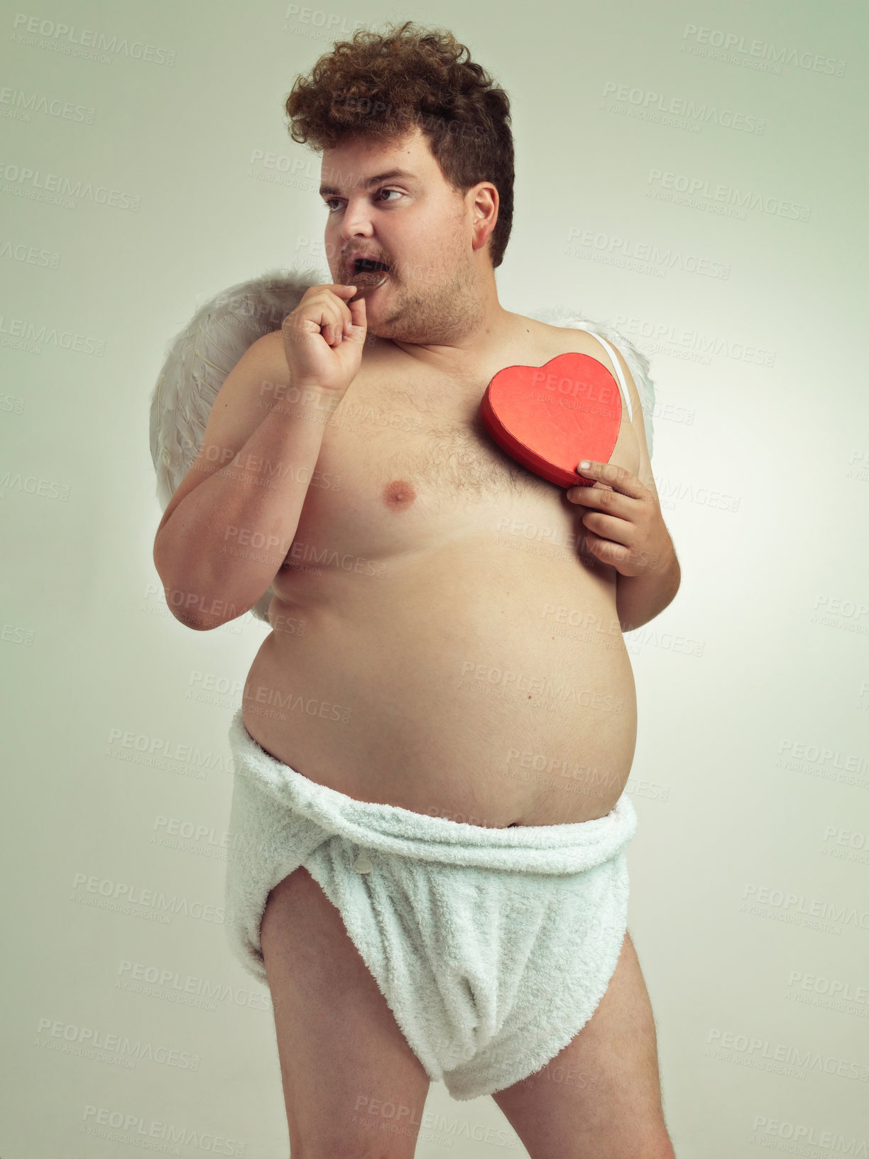 Buy stock photo Man, cupid and heart with costume in studio for wings, bow and arrow on isolated gray background. Fantasy, chocolate and plus size male model for character role play, creative dress up or cosplay