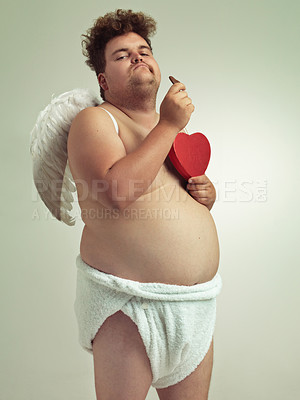 Buy stock photo An obese man dressed as a cherub eating chocolates