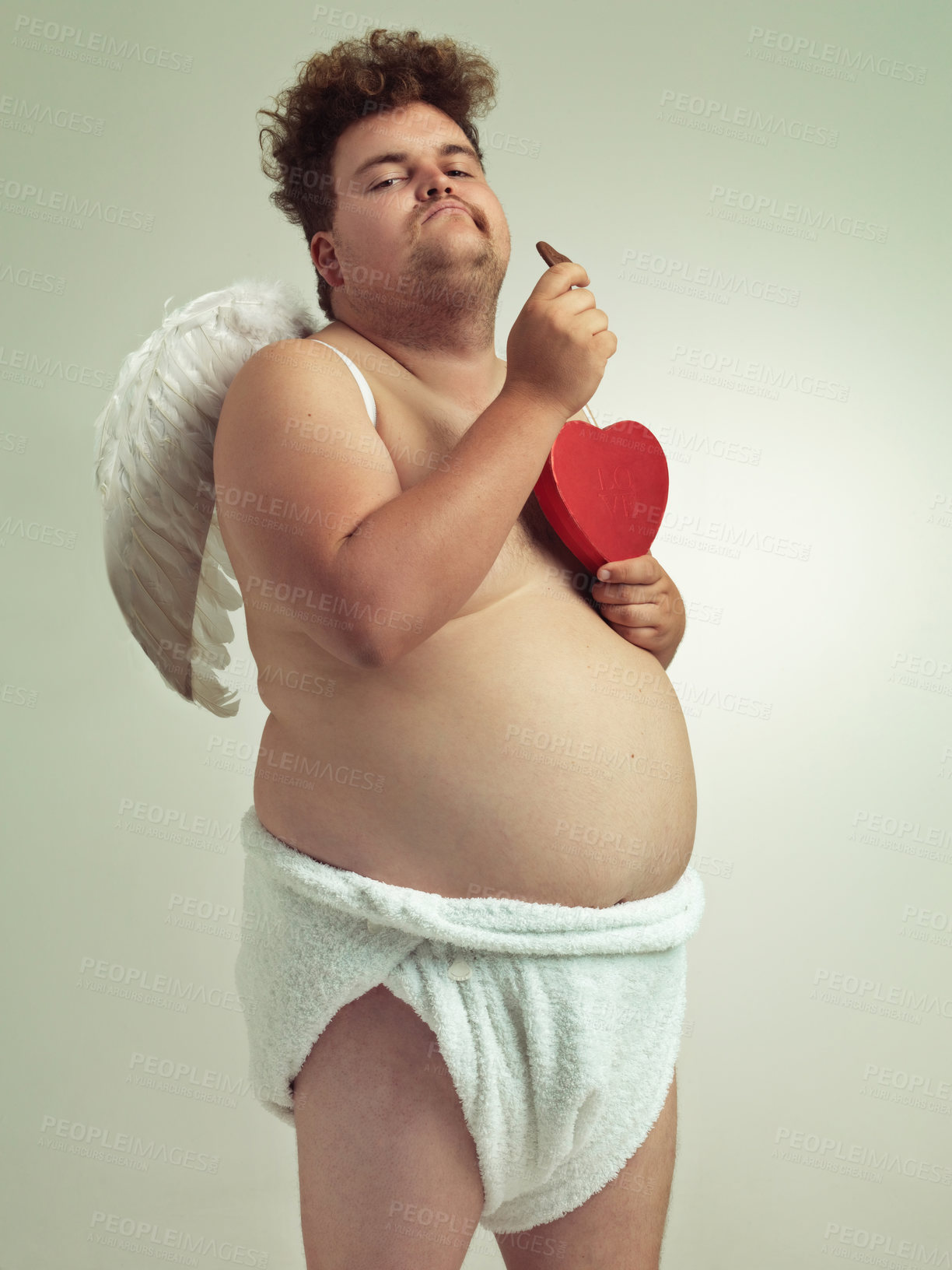 Buy stock photo An obese man dressed as a cherub eating chocolates