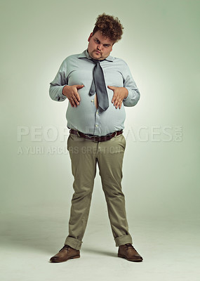 Buy stock photo Business man, portrait and plus size with stomach gesture, joke and silly in a studio with funny face. Goofy, employee and office fashion with fun and modern clothing with green background and humor