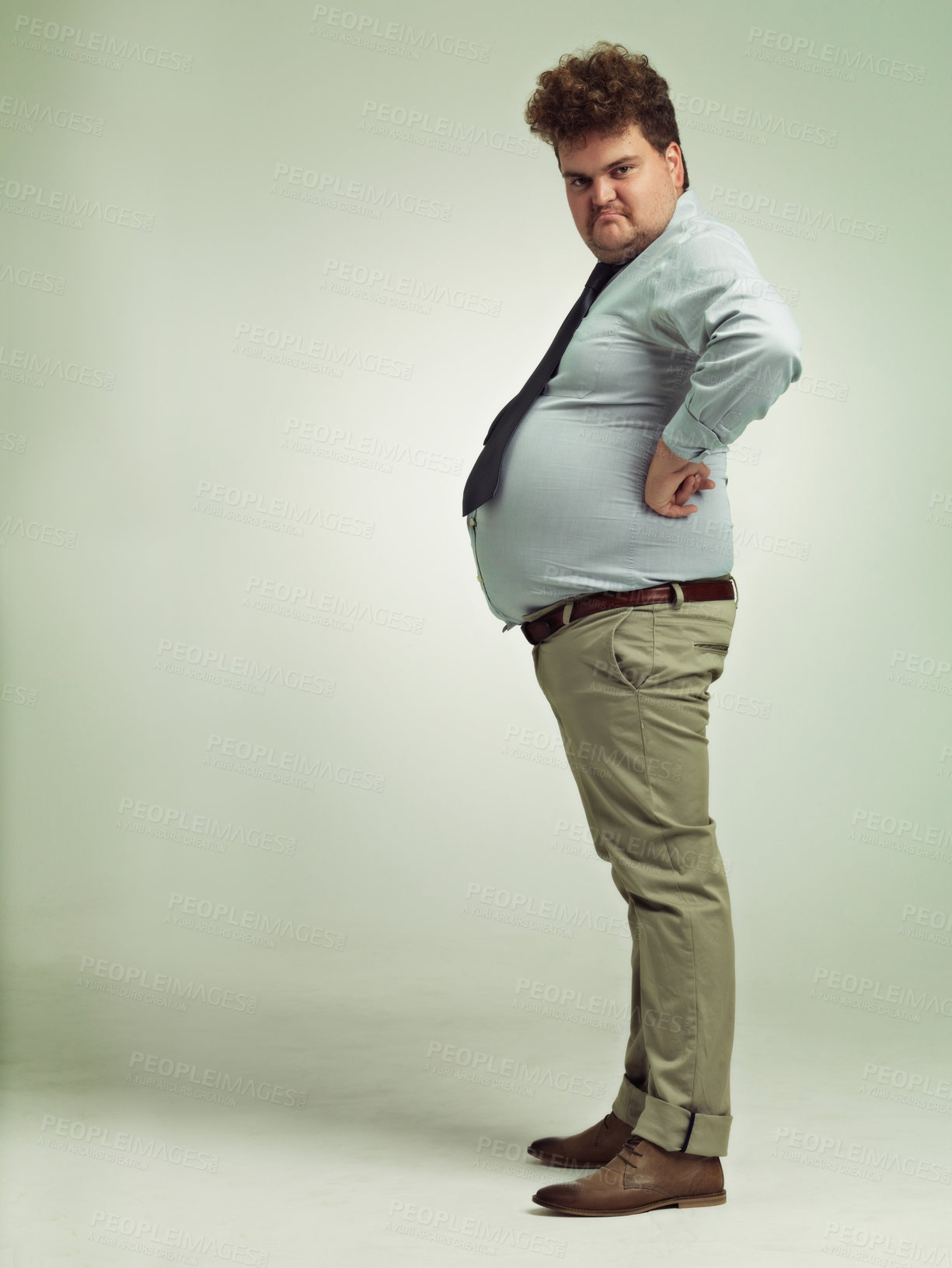 Buy stock photo Business man, portrait and plus size with grumpy, joke and silly in a studio with arms on hips. Goofy, employee and office fashion with comedy and clothing with green background and funny humor