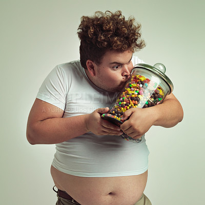 Buy stock photo Love, candy and plus size man kissing glass jar in studio on gray background for craving or hunger. Food, obsession or possessive and crazy young person with lots of sugar for unhealthy eating
