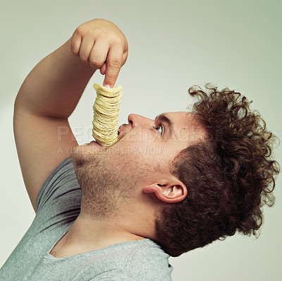 Buy stock photo Overweight, eating and man with chips in studio for unhealthy, potato and salty snack. Plus size, food and profile of male person enjoying stack of crisps in mouth isolated by gray background.