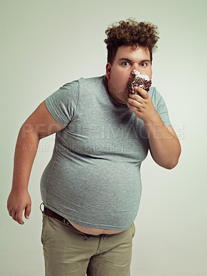 Buy stock photo Chocolate, portrait and plus size man with eating, dessert and cupcake in a studio. Overweight, sweet and unhealthy snack for fast food and hungry with funny male person with green background