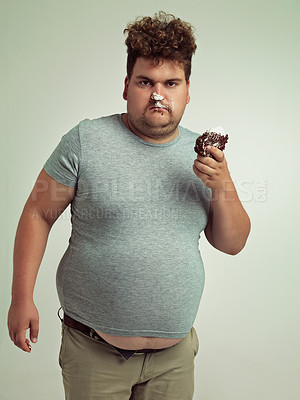 Buy stock photo Chocolate cake, portrait and plus size man with grumpy, dessert and candy in a studio. Silly, sweet and unhealthy snack for eating with junk food and hungry person with green background with joke