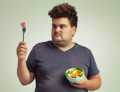 Buy stock photo Plus sized, man and unhappy with food for healthy diet, fork or bowl and salad for wellness on studio background. Male person, detox and lose weight for health, eating disorder and nutrition 