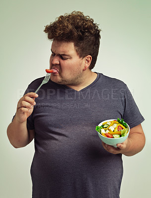 Buy stock photo Man, salad and eating with disgust in studio for healthy diet, nutrition and unhappy for weight loss. Plus size, male person and fork with tomato for vitamin c, detox or organic food for lifestyle