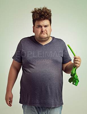 Buy stock photo Shot of an unhappy overweight man holding a celery stick