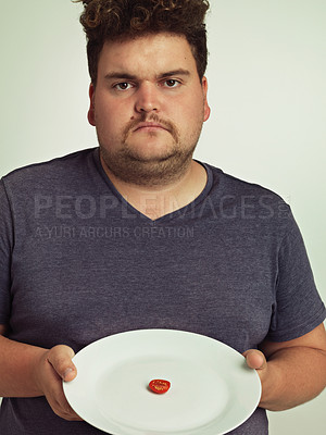 Buy stock photo Portrait, nutrition or plate and plus size man in studio on gray background, unhappy with meal limit. Food, health or diet and disappointed young person frustrated with tiny tomato slice serving