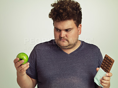 Buy stock photo Man, apple and chocolate in studio with thinking for healthy food, diet or sweet snack for wellness. Plus size, male person and choice with decision for fruit, dessert and nutrition for candy