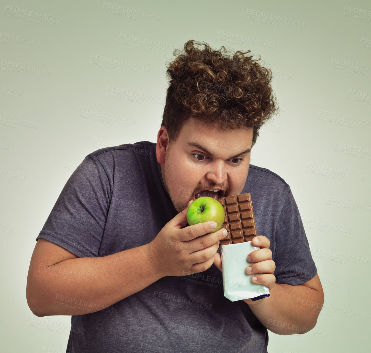 Buy stock photo Person, apple and chocolate in studio with choice of junk food, sweet or diet for wellness. Plus size, man eating and decision, fruit or candy for nutrition, lose weight and healthy lifestyle