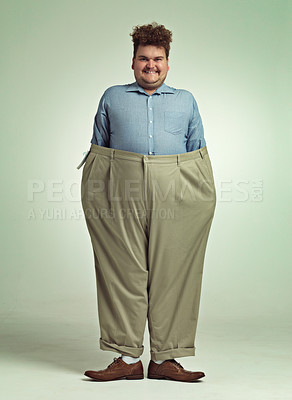Buy stock photo Shot of an overweight man wearing a pair of oversized pants looking pleased