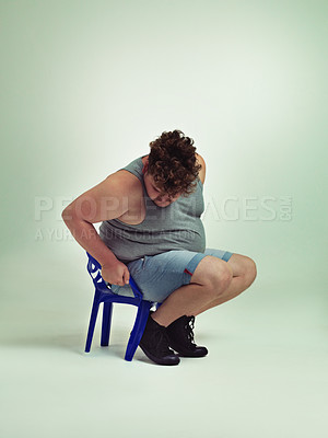Buy stock photo Shot of an overweight man trying to fit into a small chair