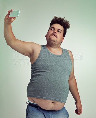 Buy stock photo Selfie, fashion and plus size man in studio posing with casual, trendy and cool outfit with stomach. Style, serious and crazy male person with photography picture isolated by gray background.