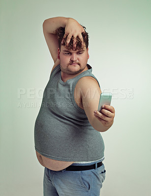Buy stock photo Selfie, cellphone and plus size man in studio posing with casual, trendy and cool outfit with stomach. Phone, serious and funny with male person with photography picture isolated by gray background.