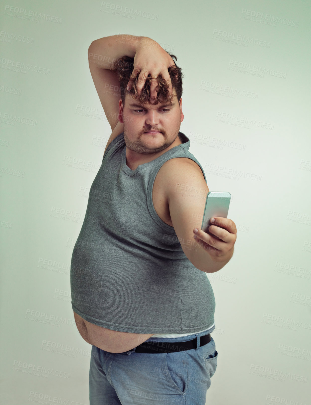 Buy stock photo Selfie, cellphone and plus size man in studio posing with casual, trendy and cool outfit with stomach. Phone, serious and funny with male person with photography picture isolated by gray background.