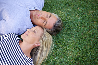 Buy stock photo High angle shot of a mature couple lying in the park