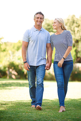 Buy stock photo Full length portrait of mature couple walking hand-in-hand in the park
