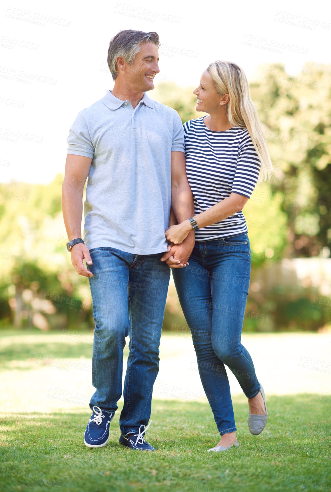 Buy stock photo Full length shot of mature couple walking hand-in-hand in the park