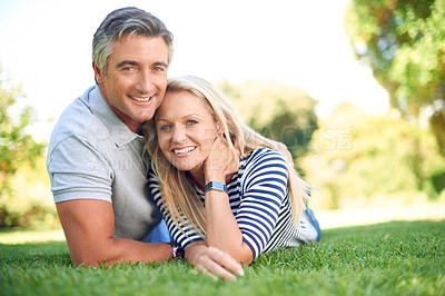 Buy stock photo Full length portrait of an affectionate mature couple lying in the park