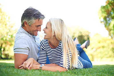 Buy stock photo Full length shot of an affectionate mature couple lying face to face in the park