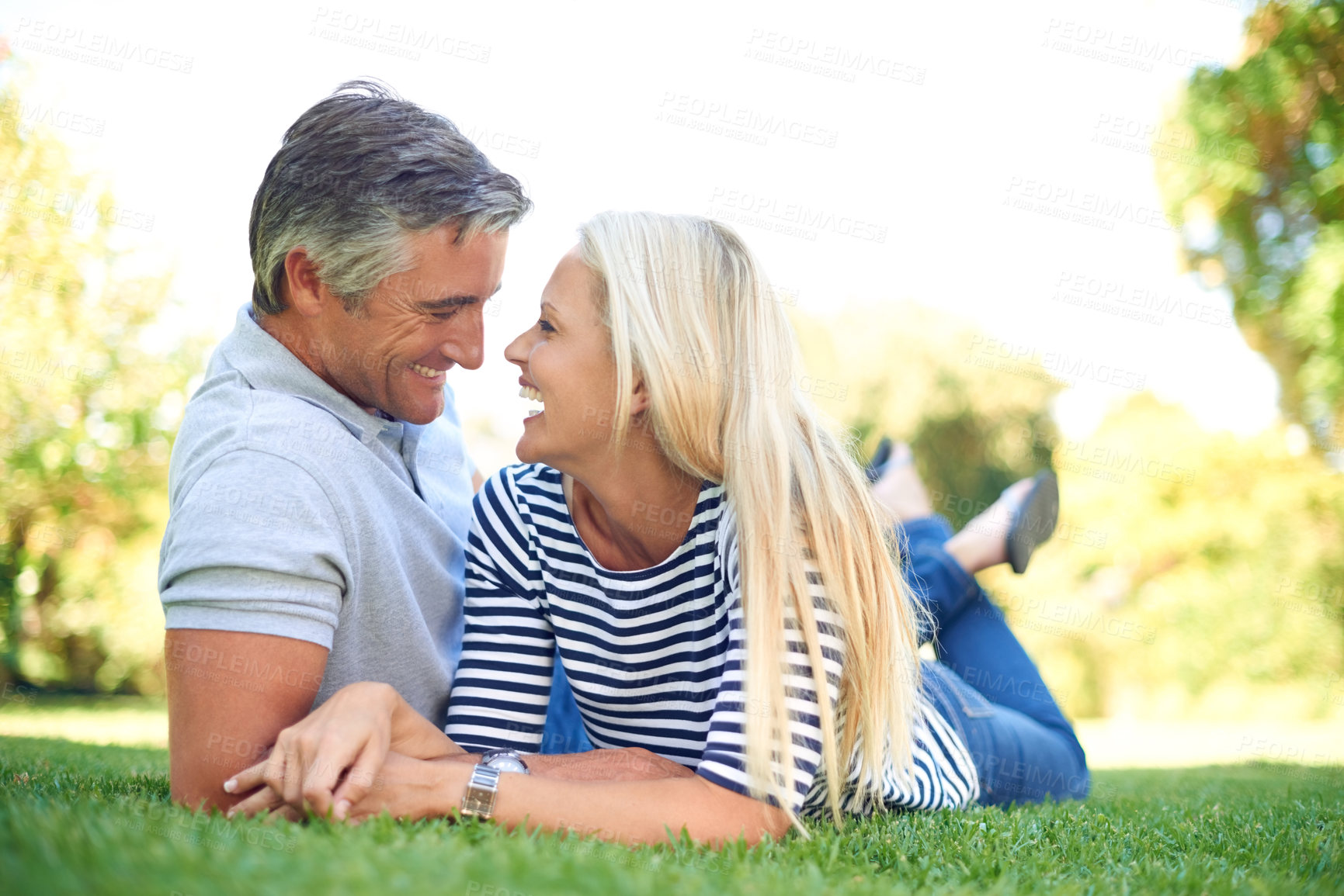 Buy stock photo Laugh, relax and couple on lawn outdoor at park for love, care and romantic date. Happy woman, mature man and lying on grass at garden for funny conversation, joke and bonding together for connection