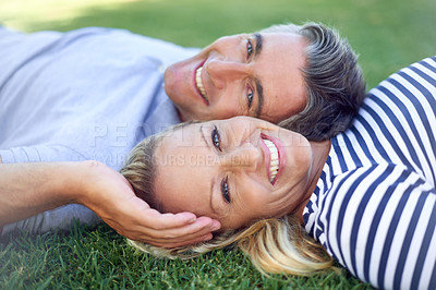 Buy stock photo Cropped portrait of an affectionate mature couple lying in the park
