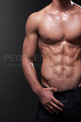 Buy stock photo Studio shot of a handsome bare-chested young athlete standing against a black background