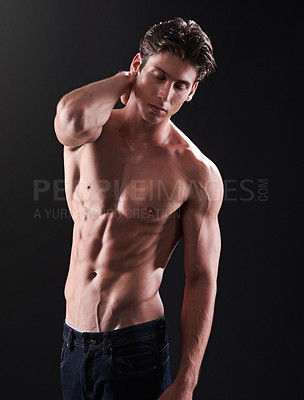 Buy stock photo Studio shot of a handsome bare-chested young athlete standing against a black background