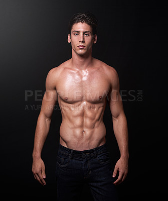 Buy stock photo Studio shot of a handsome bare-chested young athlete standing against a black background